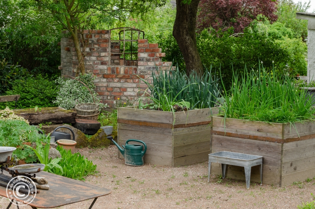 Gartengestaltung mit Hochbeeten und alter Backsteinmauer