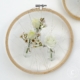 Stickrahmen als Wanddeko mit kleinen Blumenvasen mit Waxflower und Eustoma