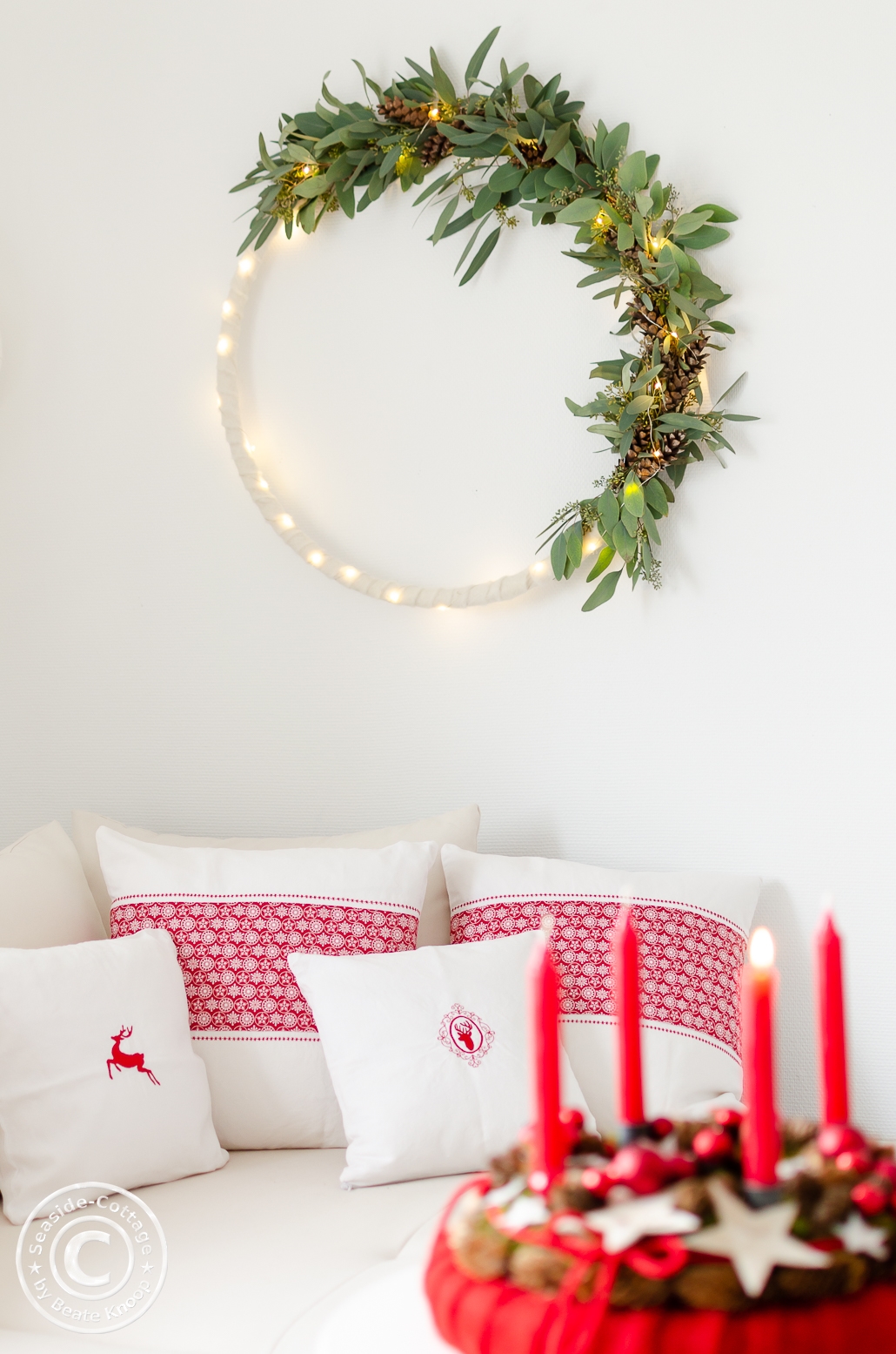 weihnachtliche Wanddeko mit Hulahoop bewickelt mit Eukalyptus, weißem Filz und Lichterkette