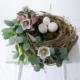 Nest aus Rebe dekoriert mit Eukalyptus, Lenzrosen und Gänseeiern