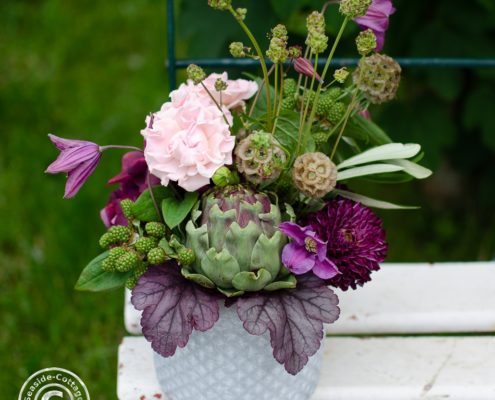 Sommerliche Tischdeko mit Artischocke, rosa Rosen, Hortensie, Dahlien, Waldreben, grünen Brombeeren und Wiesenknöpfchen
