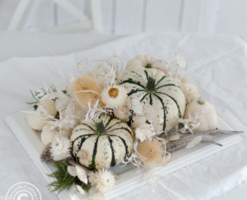 Tischdeko mit weißen Kürbissen und Trockenblumen auf einem weißen Tisch mit weißer Tischdecke