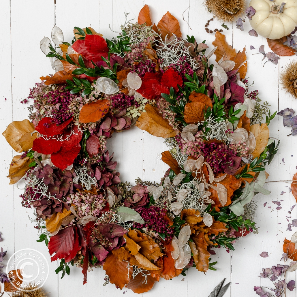 Bunter Herbstkranz auf weißen Holzbrettern