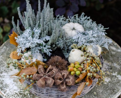 herbstliche dekorierter Pflanzring auf einem verwittertem Gartentisch