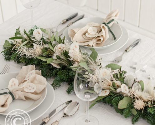 Festlich gedeckter Tisch zu Weihnachten mit Trockenblumengirlande im Bohostil